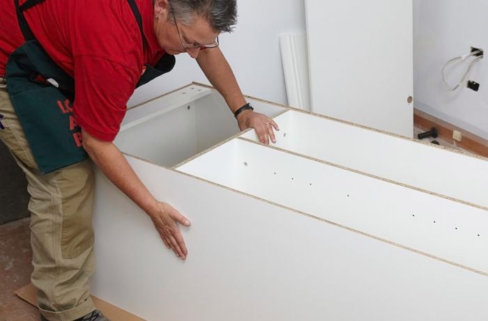 Person attaching broom cupboard together.