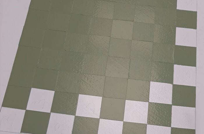 Green paint is used to paint over the paint to form the checkered pattern of the chess board