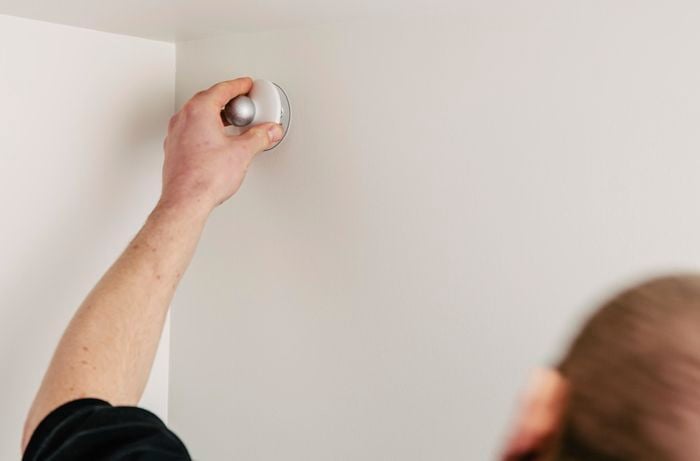 A person installing a security camera high up on a wall
