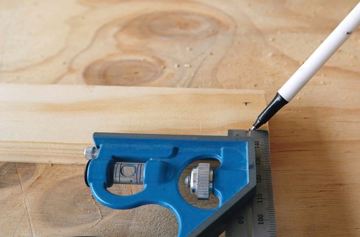 Person measuring and marking hole locations for drilling