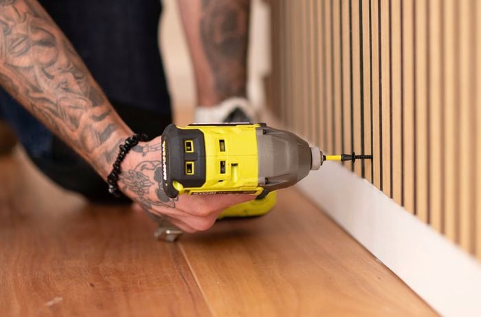 Drilling timber panels onto the walls.