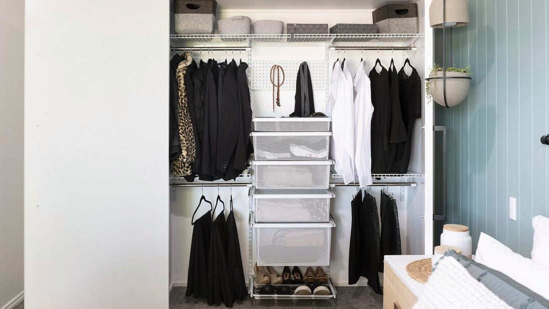 An empty wardrobe with hangers, wire mesh drawers, a pegboard and overhead wire rack