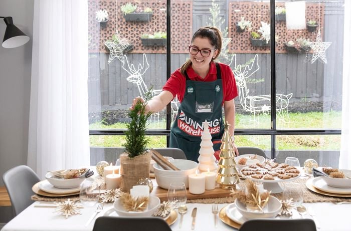 Woman adding finishing touches to dining table decorated for Christmas