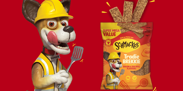Schmackos Tradie Brekkie dog treats pack beside a construction-themed dog character wearing a hard hat and high-vis vest.