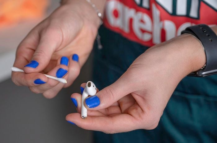 Removing dirt and earwax from airpods using cotton swab. 