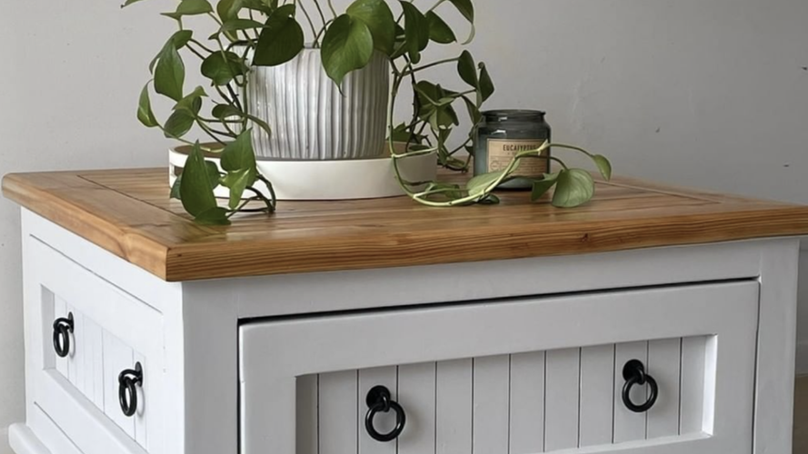 White side table finished with clear varnish along with plant and candle on top. 