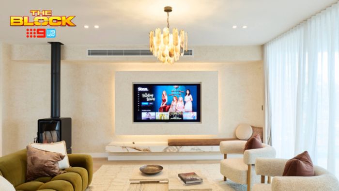 Contemporary living room featuring a wall-mounted TV, wood-burning fireplace, statement chandelier and neutral seating.