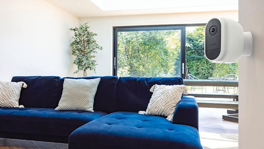 Indoor living space with couch and pillows and security camera on wall