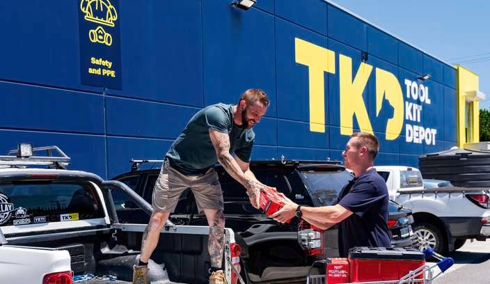 TKD team member and customer loading Milwaukee tools into a ute outside a TKD store