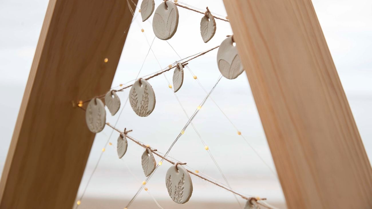 Close up of a wooden Christmas tree with fairy lights and decorations strung across the frame.