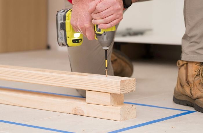  A person is using a power drill to fix the top timber rail.