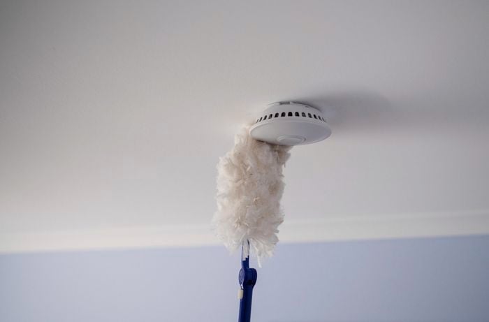 Cleaning the smoke alarm using a duster.
