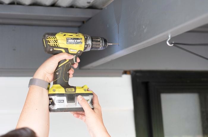 A Bunnings team member drilling into a patio roof beam
