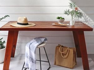 Timber table with hat and bowl of fruit on it.