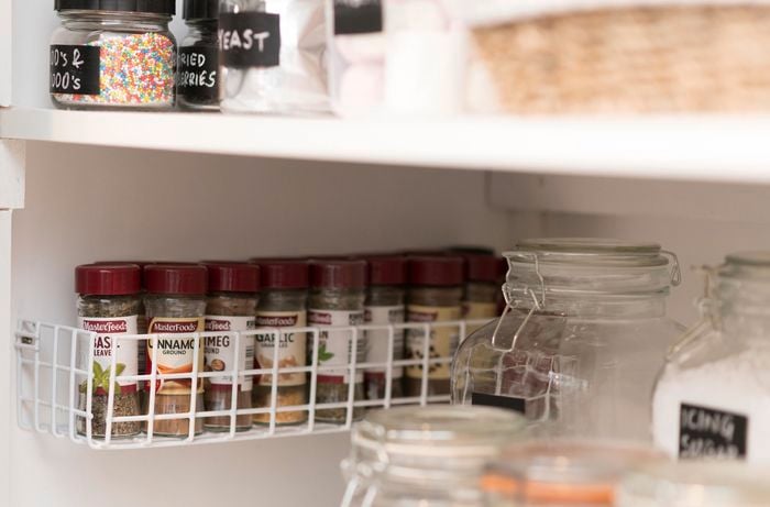 Basket attached to wall with spice jars in it.