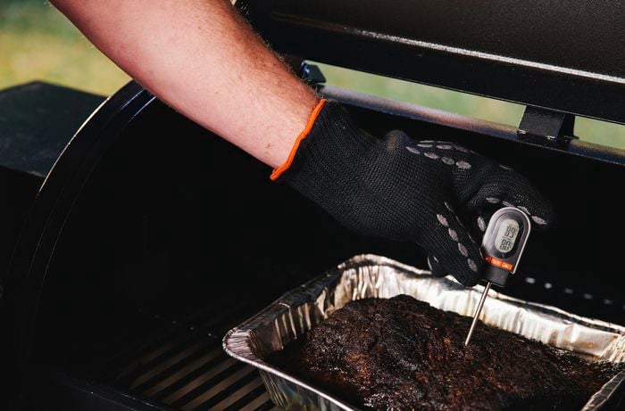 A probe being used to check the temperature of a cooking brisket