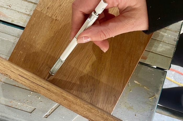 Person uses marker to mark up plank of wood