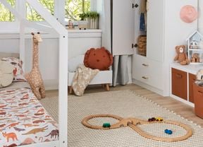 Kids bedroom with white toddler bed and cupboard, printed ceiling light shade and horizontal storage cabinet with brown drawers and white walls