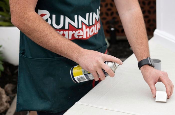 A wooden drawer handle being spray-painted with a basecoat of white