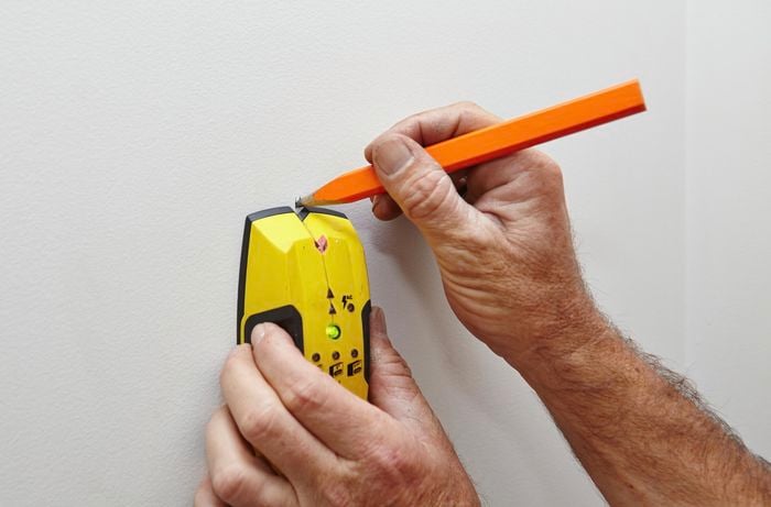 Marking the location on the wall with a pencil.