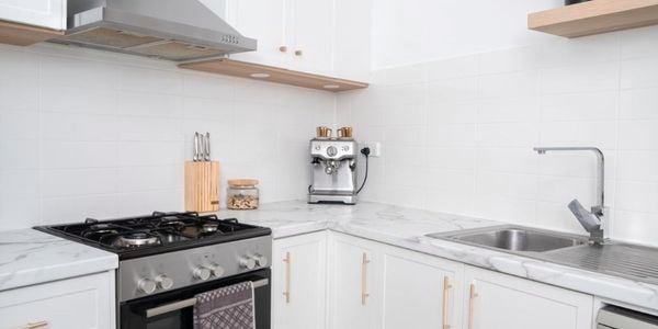 A kitchen with white cabinets and stainless steel oven and rangehood