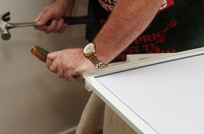 A person using a hammer and chisel to remove door guides from a mirror door