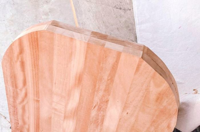  Overhead shot of a wood plank with curved edges standing upright on concrete.