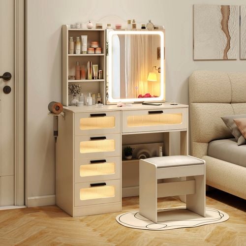 Beige dressing table, with a stool, bed and a print on the wall in a bedroom.