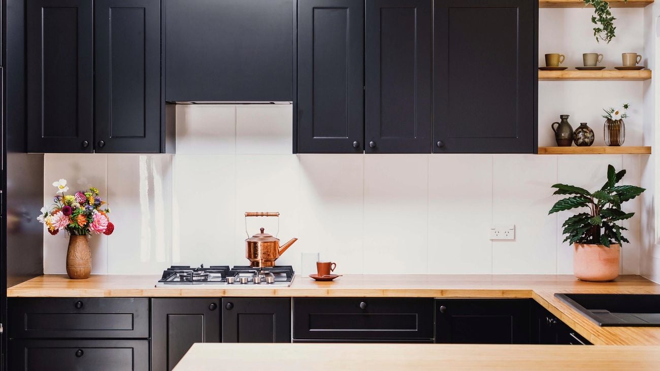 A warm kitchen featuring black cabinetry and a timber benchtop.