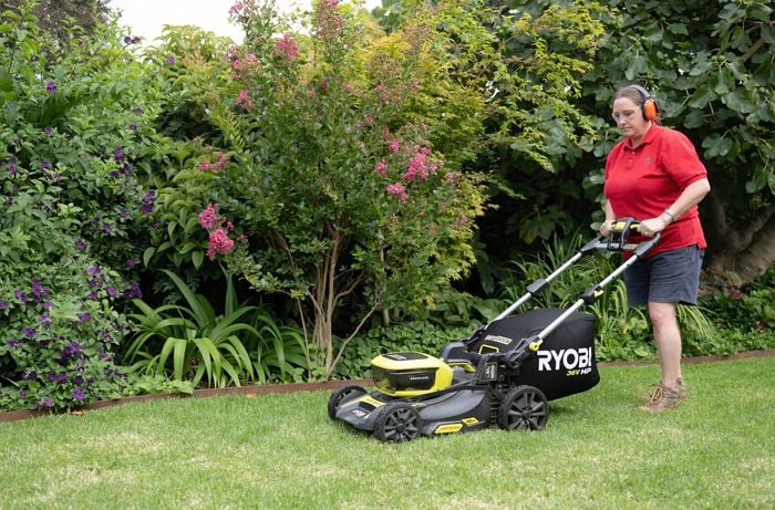 Using brushless cordless lawn mower to mow the lawn.
