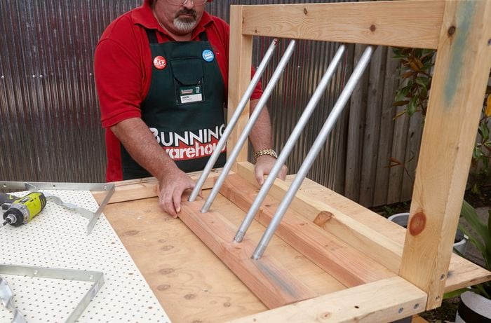 A person positioning two timber sections joined by galvanised pipes