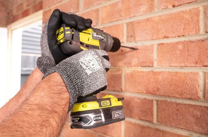 Person drilling into brick wall.
