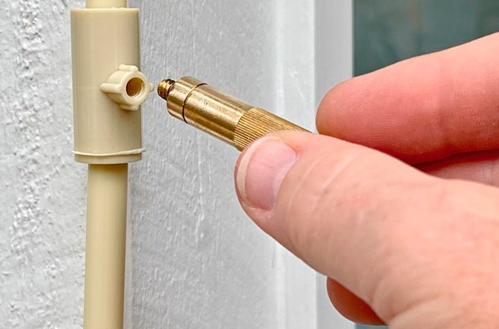 A person attaching an auto-drain valve
