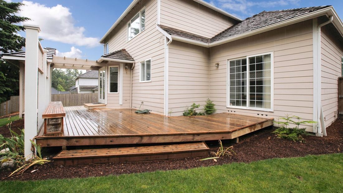 Two-storey weatherboard house with outdoor deck and garden