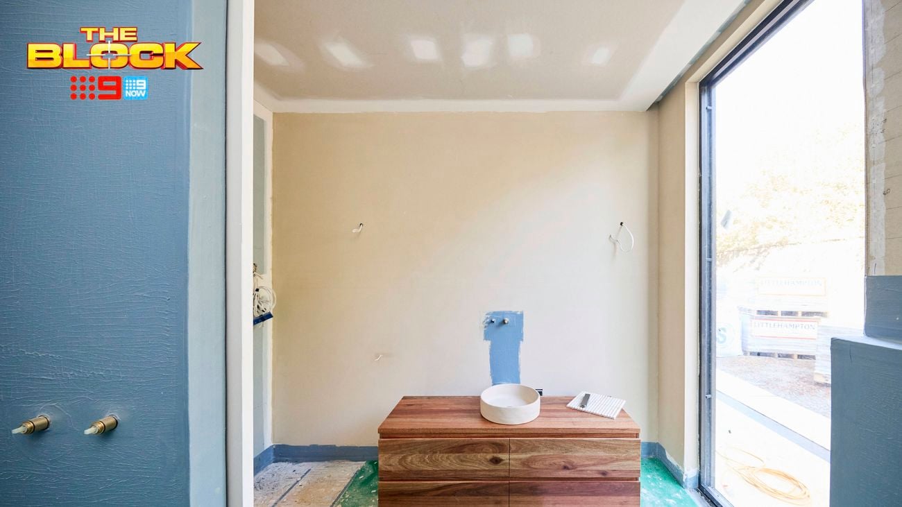 An unfinished bathroom featuring a timber vanity with a white basin, blue cabinetry, and a large floor-to-ceiling window.