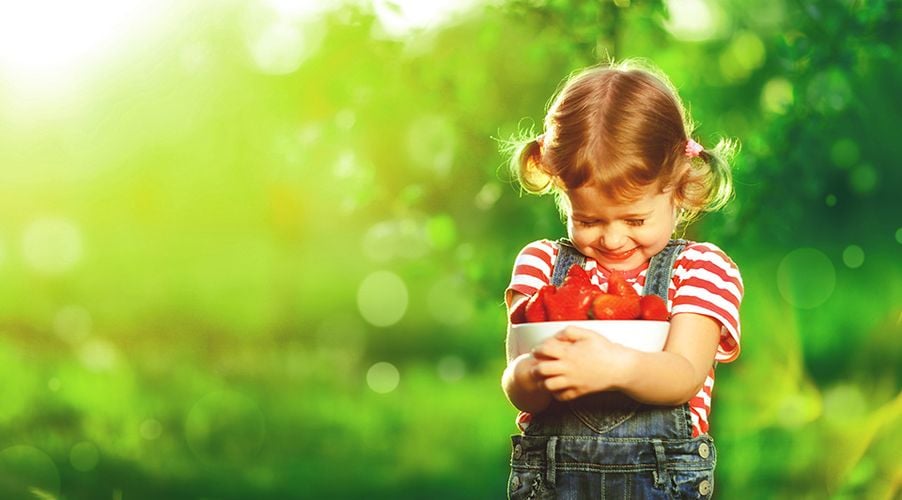 Child holding bowl of strawberries