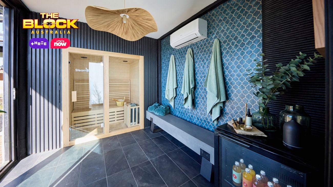 A room with towels hanging on hooks on a wall, tiled flooring, a split system attached to a wall and a print hanging on it also.