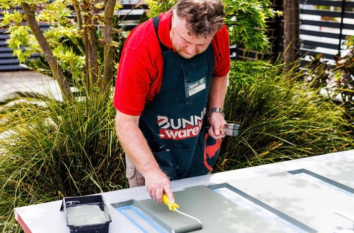 Person using a paint roller to paint a door.