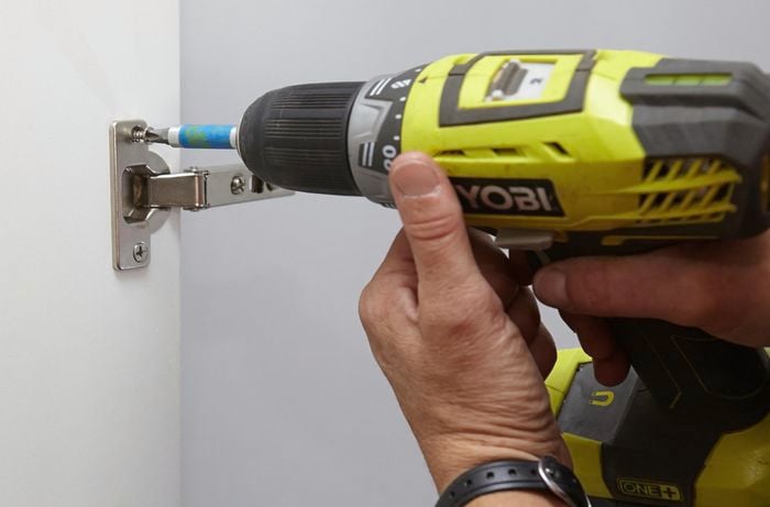 Person drilling into hinge.
