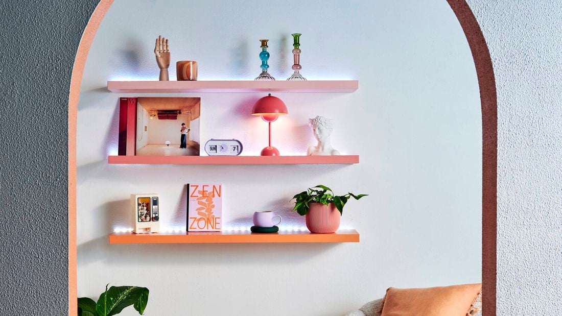 Floating shelves seen through an archway lit up with LED lights and topped with books and decor