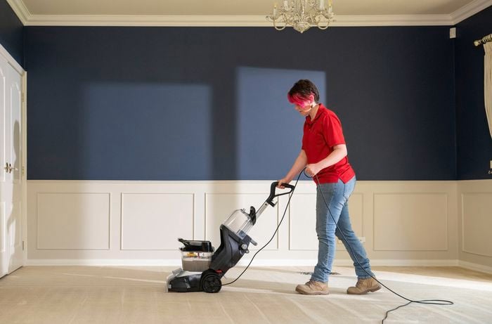  A Bunnings Team Member is rinsing a beige carpet with clean water to remove any remaining cleaning solution.