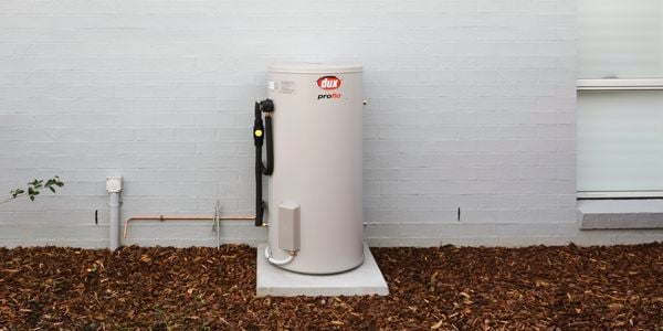 Hot water system located at the back of a rendered brick house
