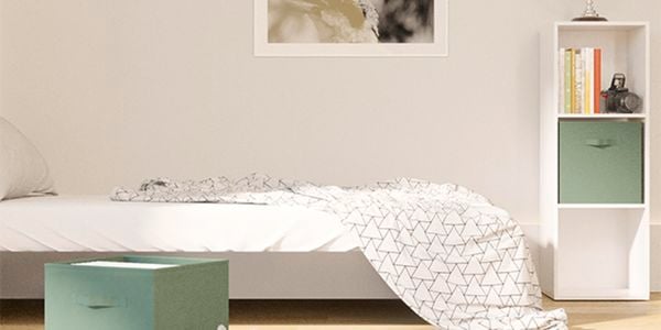 A bed in a bedroom with a shelving unit in and a picture on the wall