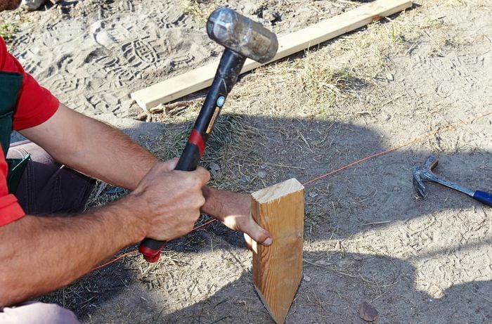 Person hammering timber into the ground.