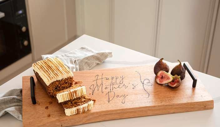 A piece of cake on a serving board with a happy Mother's Day design.