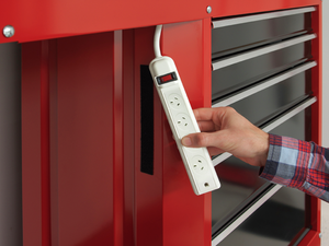 Hand holding a white power board showing a black strip of VELCRO® attached to a red bench