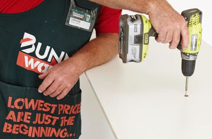 Person drilling screw into panel to attach shelf