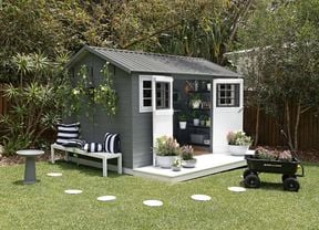 Grey and white shed in a backyard with lawn