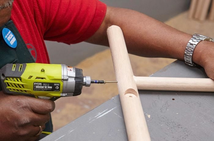 Stool legs being drilled to secure a foot rail