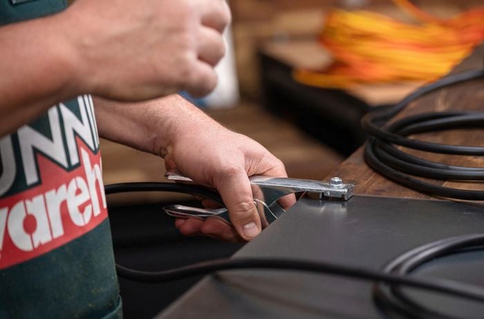Bunnings team member connecting earth clamp to arc welder.